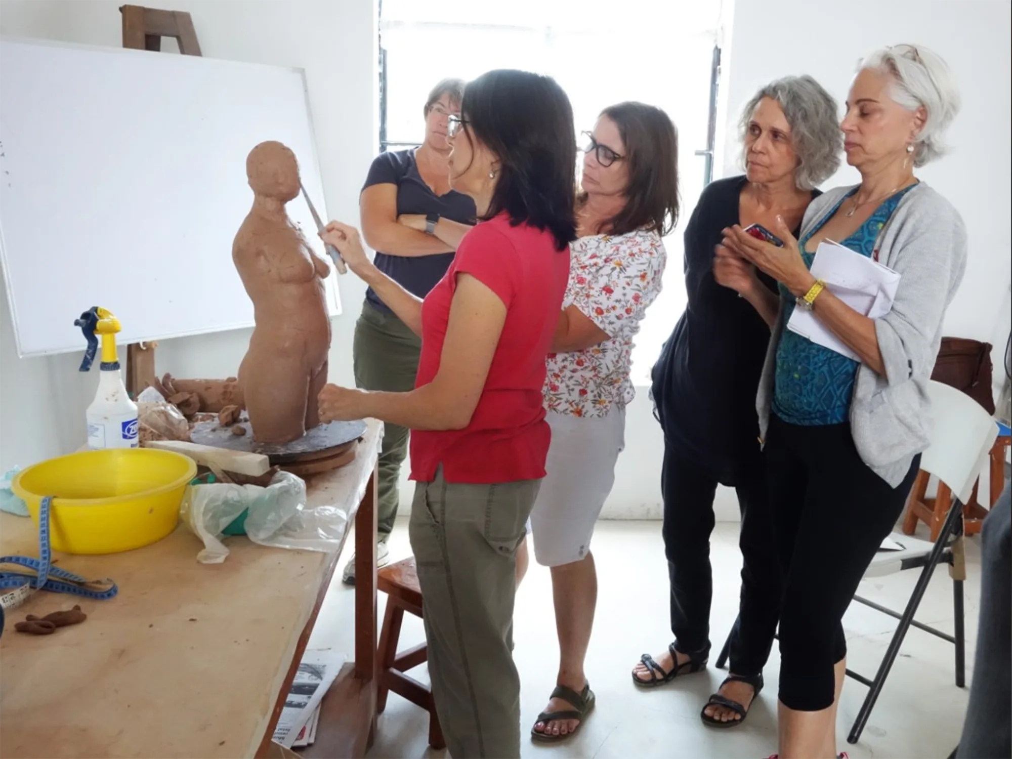 Students observing a clay sculpting demonstration